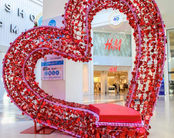 A large seat, created out of metal, in a shape of a love heart. The seat is covered in red notes of love written by members of the public.