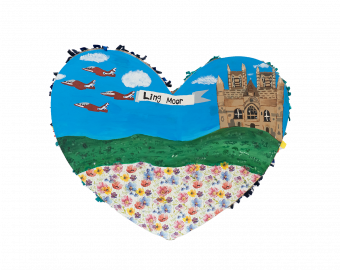 A Heart shaped sculpture, created by school children. The Heart depicts Lincoln Cathedral with the Red Arrows flying across a field. Attached a plane reads the banner, 'Ling Moor'.