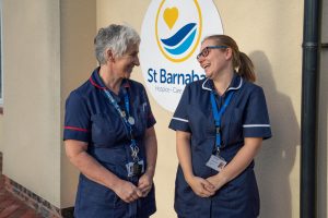 Two St Barnabas nurses, laughing and smiling, outside The Grantham Wellbeing Centre