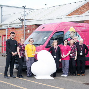 A group of people who work at Jackson's workwear, infront of a branded van, alongside the heart
