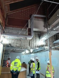 Inside the Inpatient Unit, with walls exposed, and people wearing hard hats and high-vis