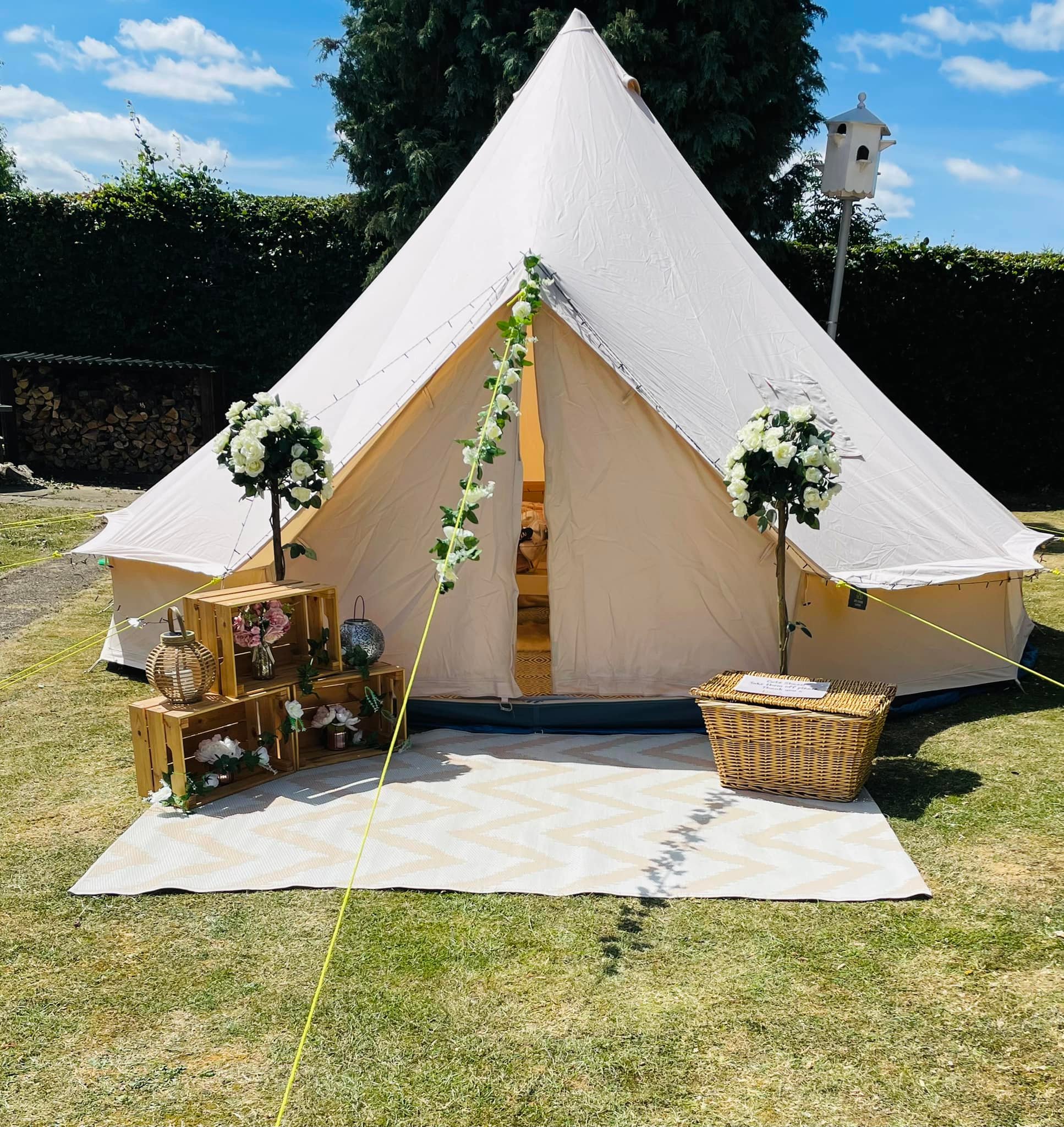 White tent with floral arrangements and wicker basket in front of opening