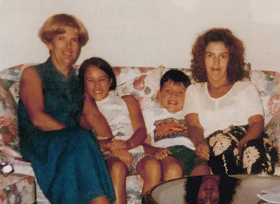 Photograph from 1990s, four people sitting on the sofa - blonde woman, young girl, young boy, brunette woman