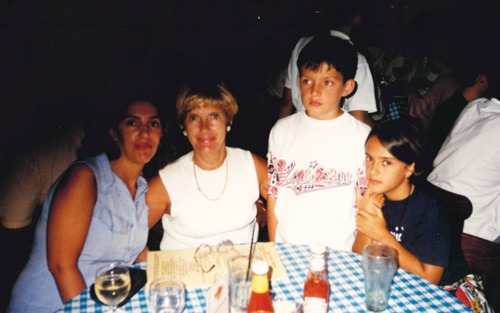 Photo from 1990s showing four people at a table, left to right: brunette woman, blonde woman, young boy and young girl