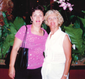 Photograph from 1990s showing woman in pink top with black handbag and blonde woman in white dress.