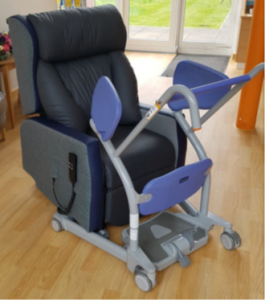 Black leather recliner chair with blue and silver medical equipment, on wooden flooring.