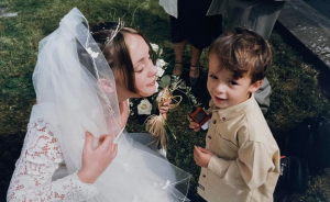 Woman in white bridal gown and veil with young boy wearing khaki jacket
