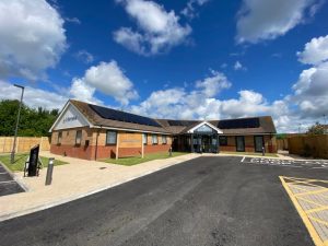 The Wellbeing Centre in Boston, with red and sandstone bricks, solar panels on roof, tarmac road