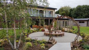 Garden space at Louth Wellbeing Centre. Plants and trees line a circular pathway with a metal arch
