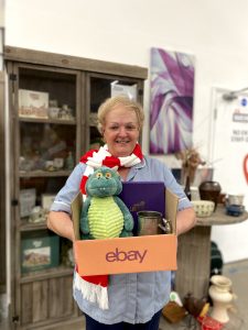 A Lady wearing a nurse uniform, holding a box of items sold on eBay, wearing a Lincoln City FC scalf.