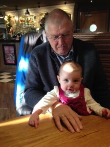 Elderly man with young child on lap at brown table