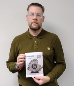 Man in green top holding paper with heart design