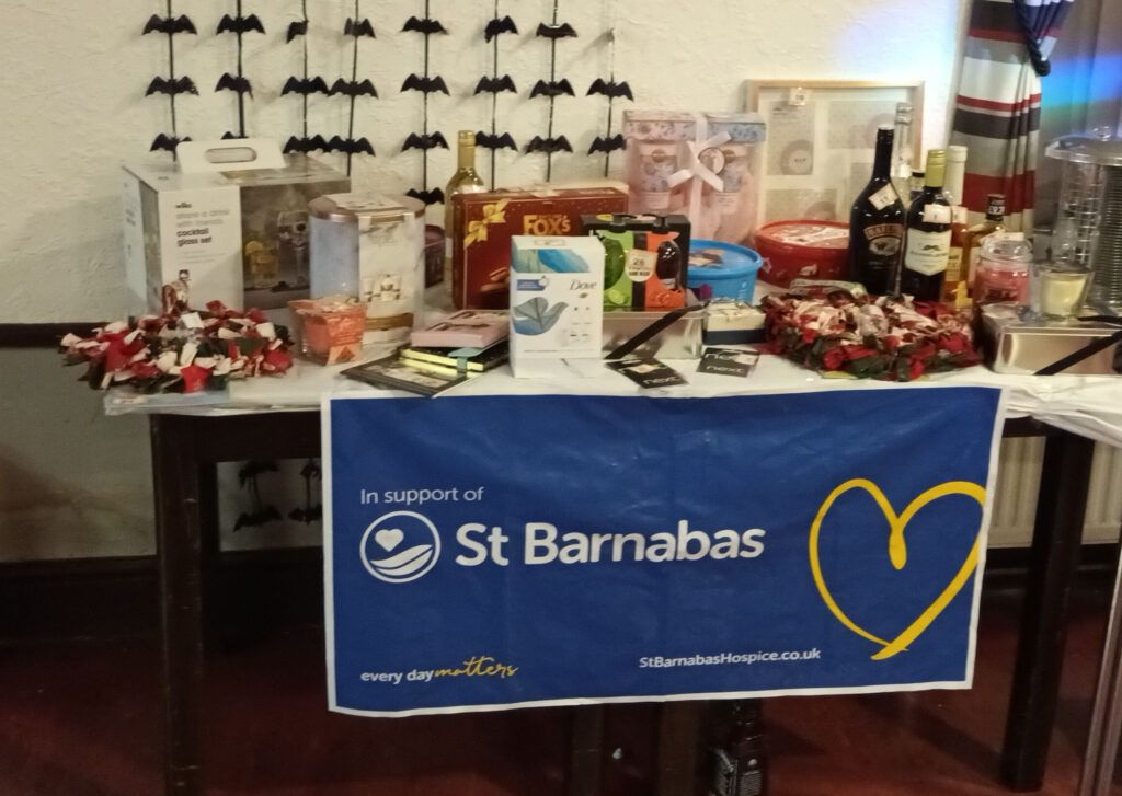 Table with items on it, and blue St Barnabas banner with yellow heart