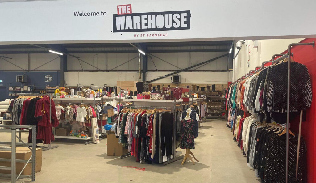 Clothing on rails with white wall and 'Welcome to the Warehouse' sign