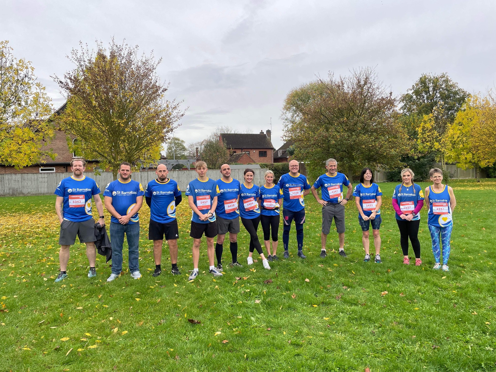 Group of men and women standing on grass wearing blue St Barnabas Hospice branded tops, ready for the 10k.