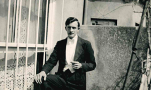 Black and white photo of dark haired man in tuxedo outdoors