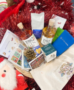 Christmas themed hamper with bottles of drink, Christmas cards, coffee bag and more