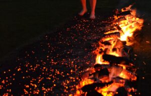 Person standing next to flaming hot wood ready to fire walk