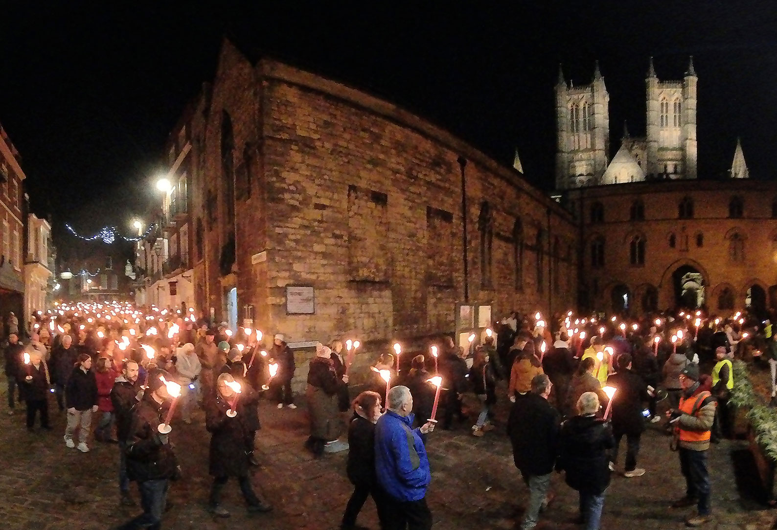 Group of people walking through Lincoln's historic Bailgate area with Lincoln Cathedral in background
