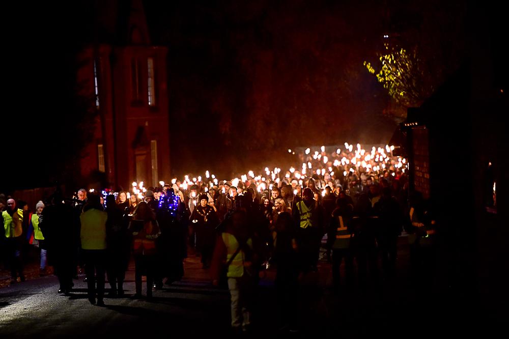 Dozens of people walking with flaming torches through the Newport arch in Lincoln's historic Bailgate area