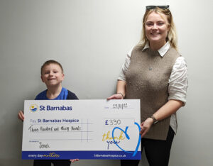Young boy and blonde woman holding large presentation cheque