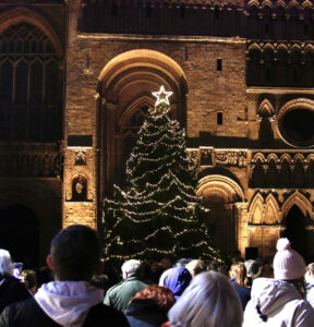 Christmas Tree with lights and star in front of Lincoln Cathedral with people gathered