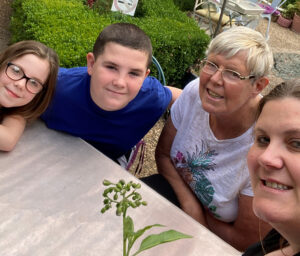 Two children and two women smiling at camera in outdoor setting