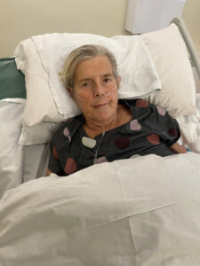 Blonde woman in hospital bed with white sheets