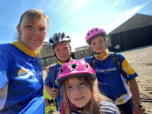 Woman and three children wearing blue St Barnabas Hospice tops, with bicycle helmets
