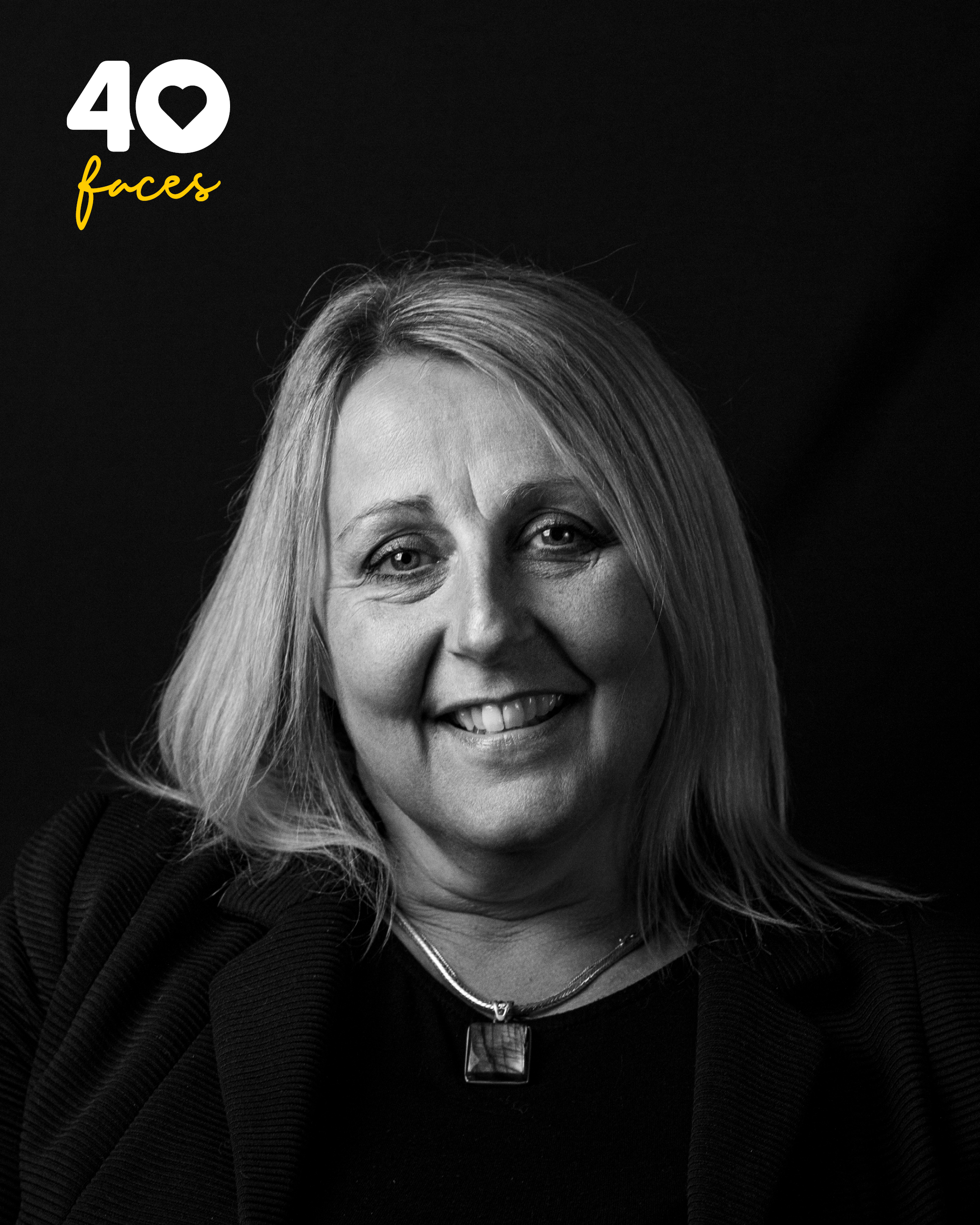 A lady, Caroline Peach, who is Head of Retail at St Barnabas Hospice, photographed in black and white, against a black backdrop