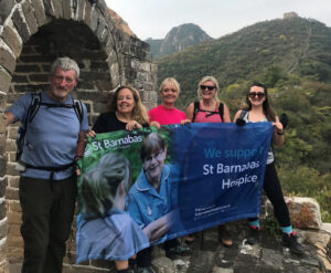 Group of people holding blue St Barnabas flag on Great Wall of China with mountain in background