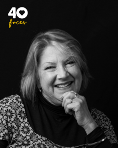 A lady, Mandy Irons, who is Head of Wellbeing at St Barnabas Hospice, photographed in black and white, against a black backdrop