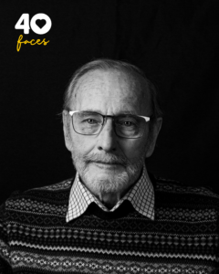 A man, Rob Glover, who is a volunteer at St Barnabas Hospice, photographed in black and white, against a black backdrop