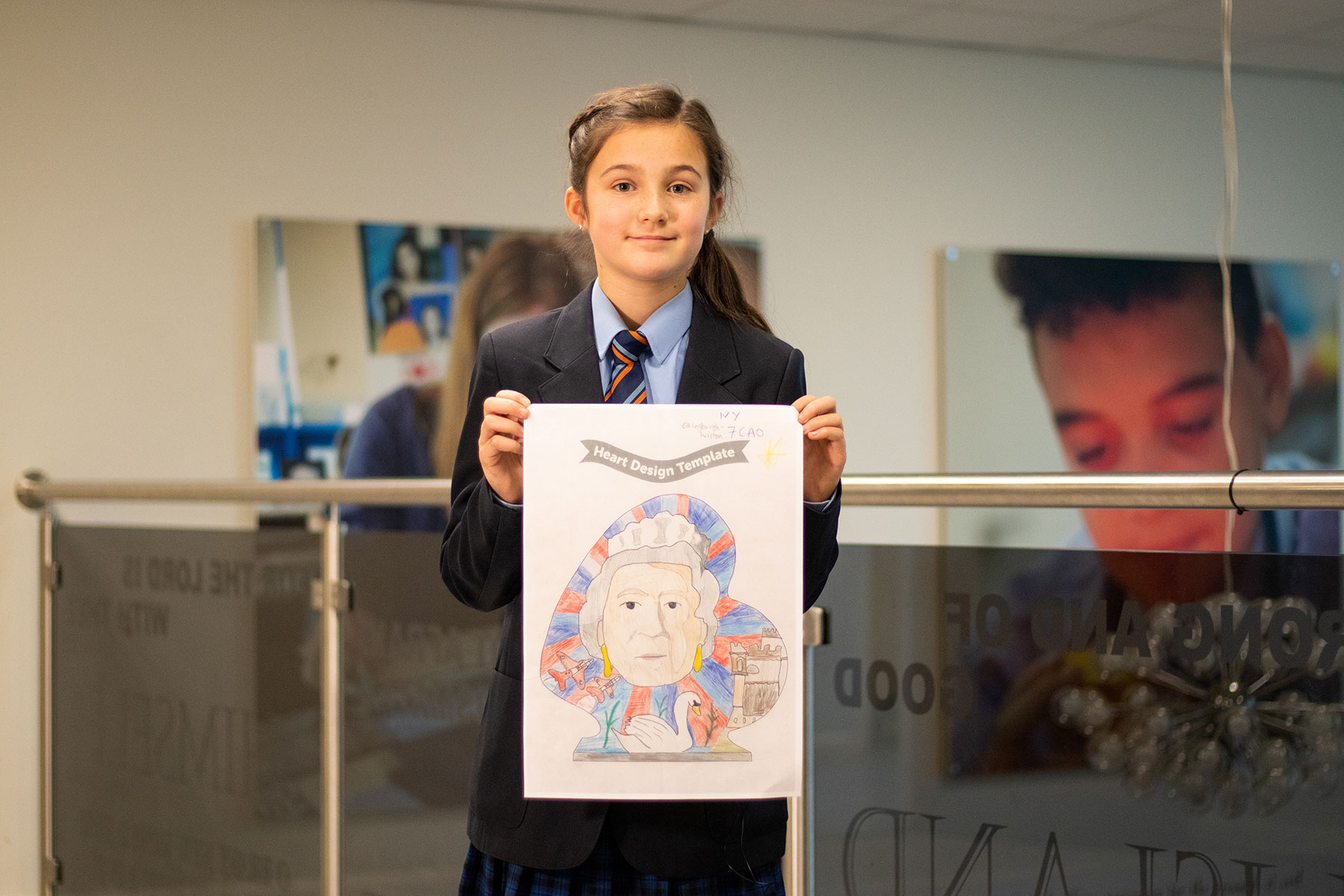 Young girl with brown hair and navy blue school uniform, holding drawing of heart shape