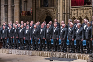 Large group of men wearing black suits singing in Lincoln Cathedral