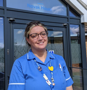 A woman, one of the St Barnabas Staff Nurses, wearing a blue tunic, stood outside the St Barnabas Wellbeing Centre in Boston, Novak House.