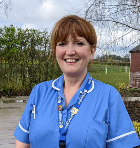 A woman, one of the St Barnabas Staff Nurses, wearing a blue tunic, stood outside the St Barnabas Wellbeing Centre in Louth.