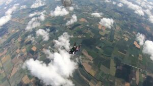 People skydiving, photo taken from above with clouds and ground visible below