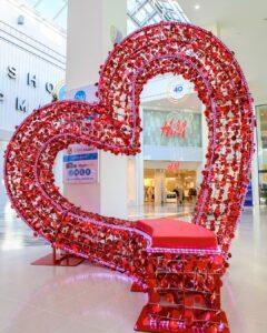 A large seat, created out of metal, in a shape of a love heart. The seat is covered in red notes of love written by members of the public.