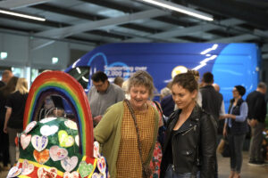 Two women looking at a heart-shaped sculpture with rainbow, part of St Barnabas Hospice's Young at HeART Trail.