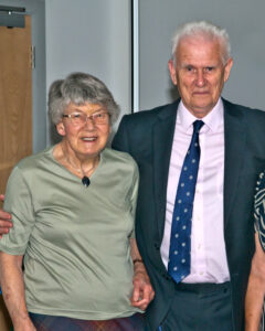 Dr Helen Walker, an elderly woman in green and Bob Neilans, man in suit with pink shirt and blue tie,