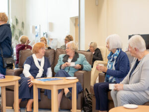 Woman sitting on brown chairs enjoying cups of tea and coffee at the Louth Wellbeing Centre by St Barnabas Hospice.
