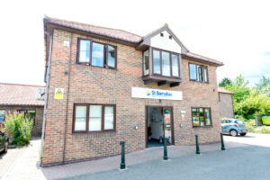 Brick building with brown detailing. White signage with St Barnabas Hospice logo.