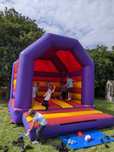 Purple, red and yellow bouncy castle with children playing.