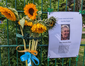 Memorial of sunflowers tied to fence with a photo of Sharon Popple, a staff member at St Peter's Dunston Primary School who passed away.
