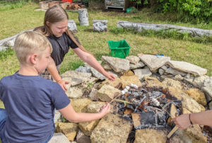 Two children sitting roasting marshmallows in a firepit