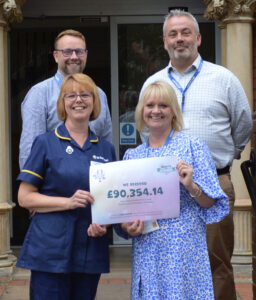 Group of people standing in front of the St Barnabas Inpatient Unit in Lincoln, holding signs with donation from Lincolnshire Co-op.