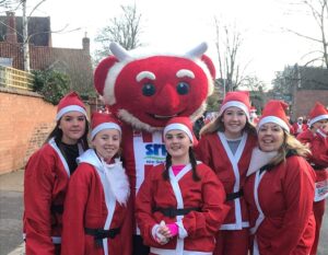 5 women, dressed in red Santa costumes, after finishing the Lincoln Santa fun run.