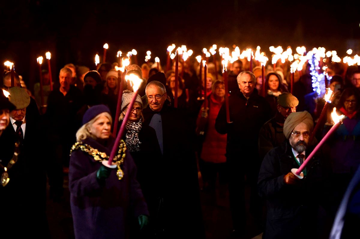 Crowd holding flaming torches as part of the Torchlight Procession