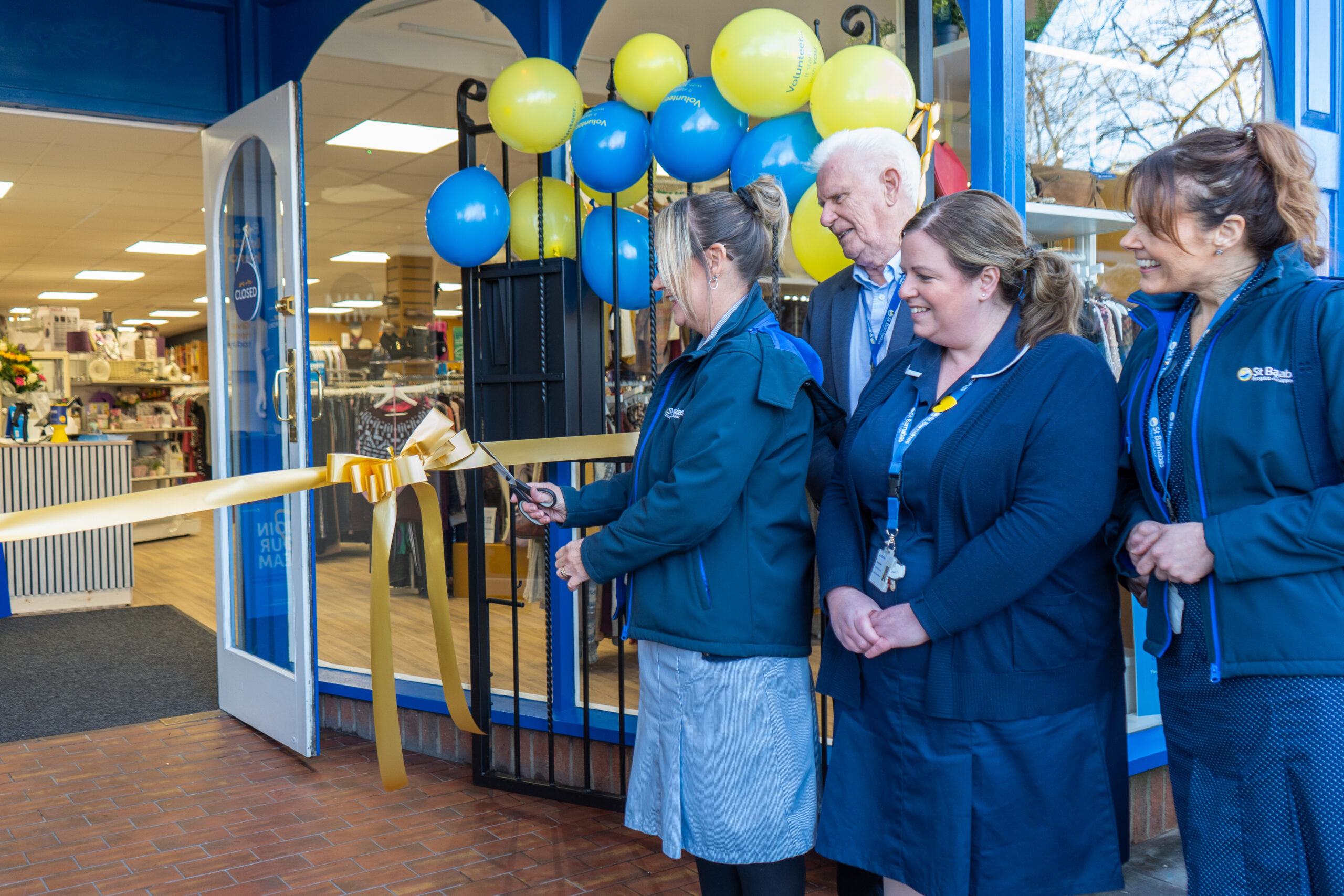 St Barnabas nurses cutting ribbon outside charity shop front